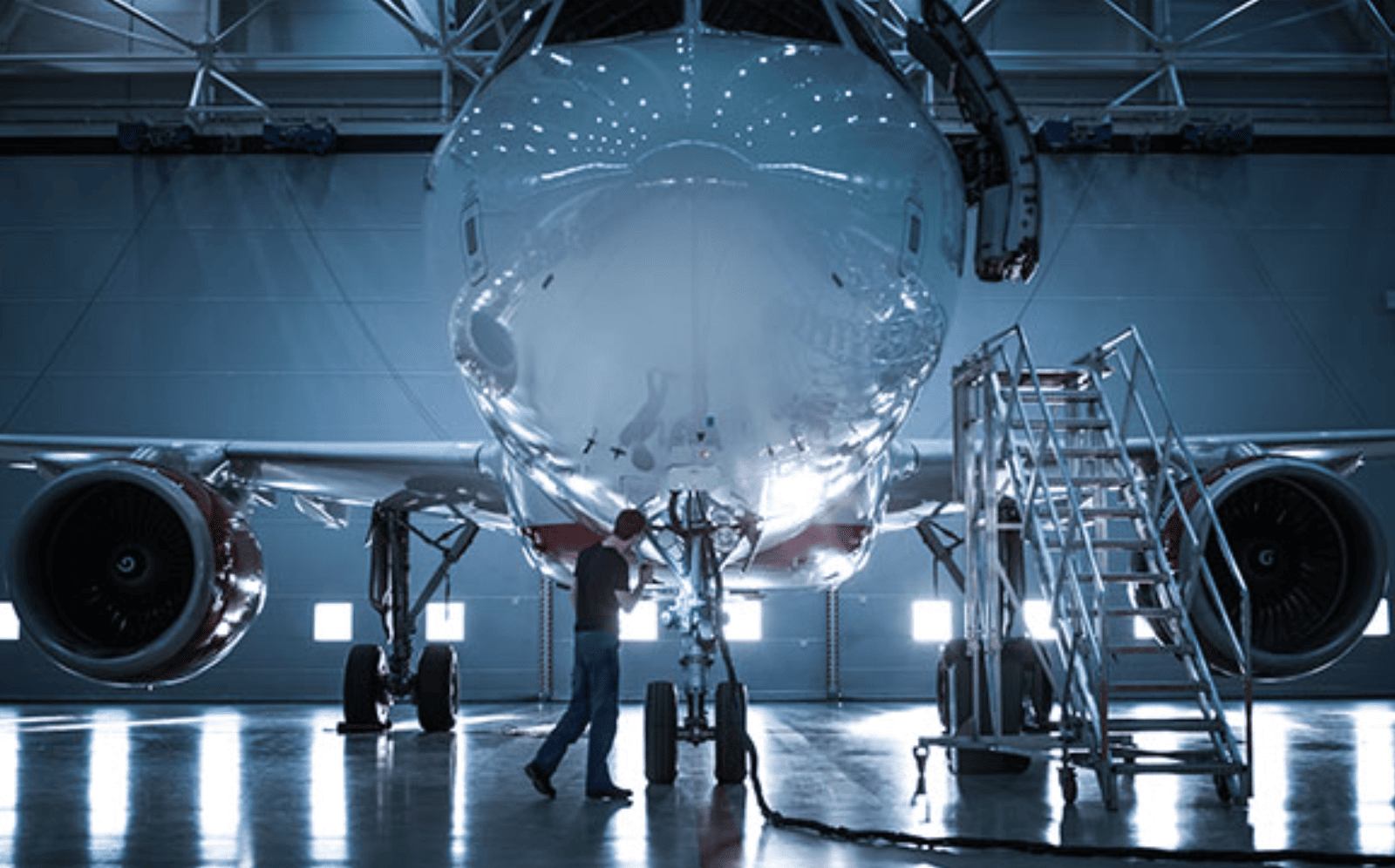 Man inspecting underside of plane in hangar